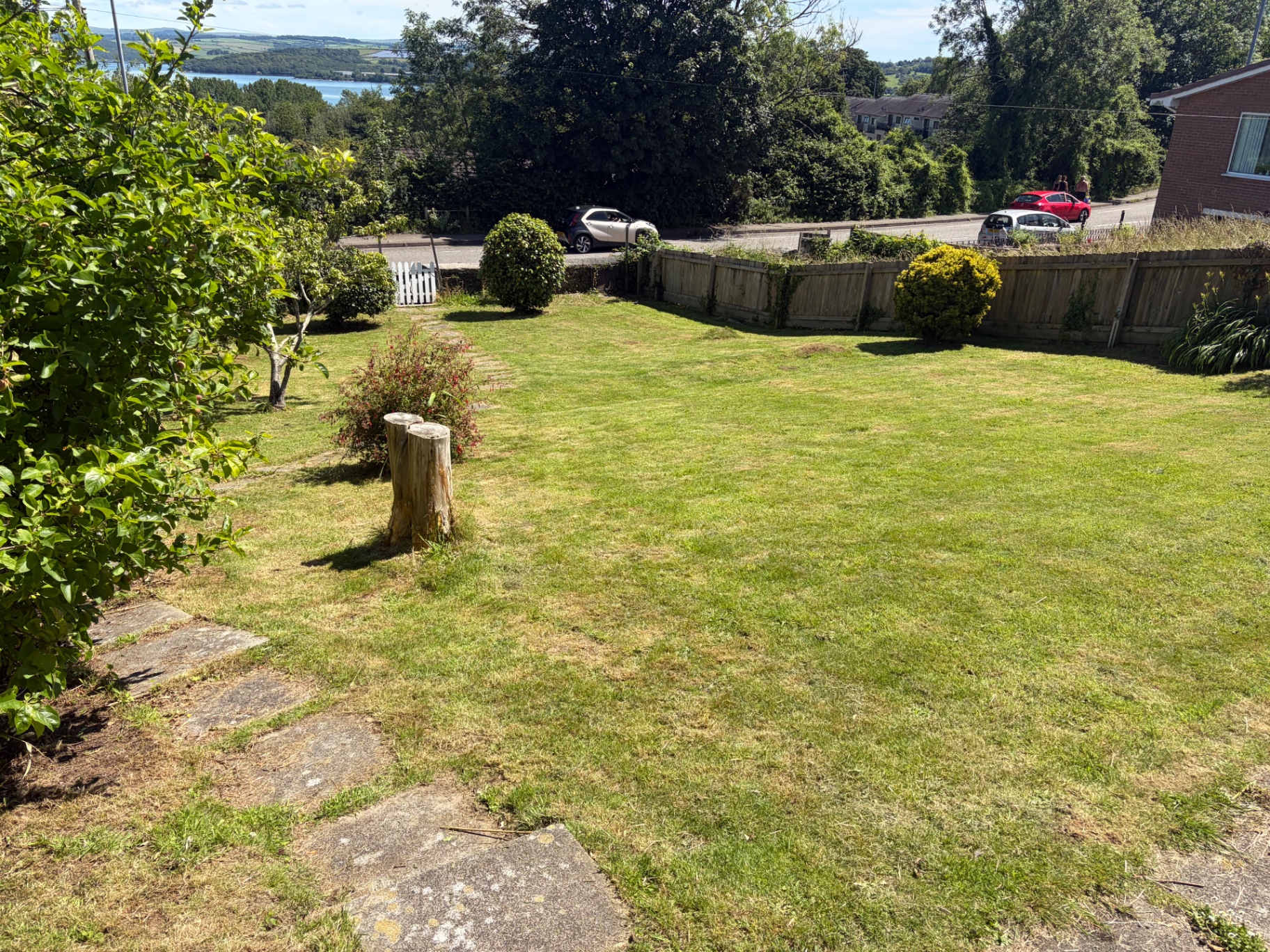 Freshly cut front lawn with shaped shrubs and distant river view